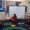 Student reading a story to other students. 