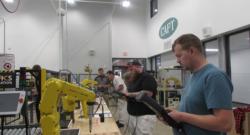 Adult students  practicing how to program a FANUC robots through the use of a teach pendant. 